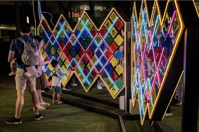 Visitors at a glowing geometric light installation