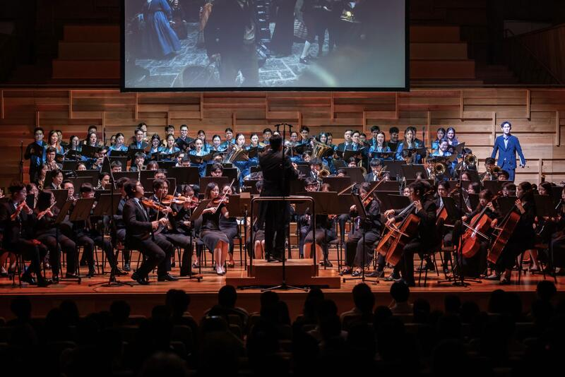 Orchestra performing under a projected screen